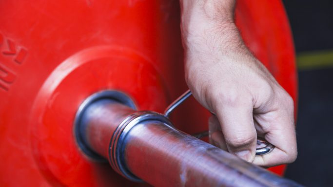 crop-hand-putting-weight-barbell